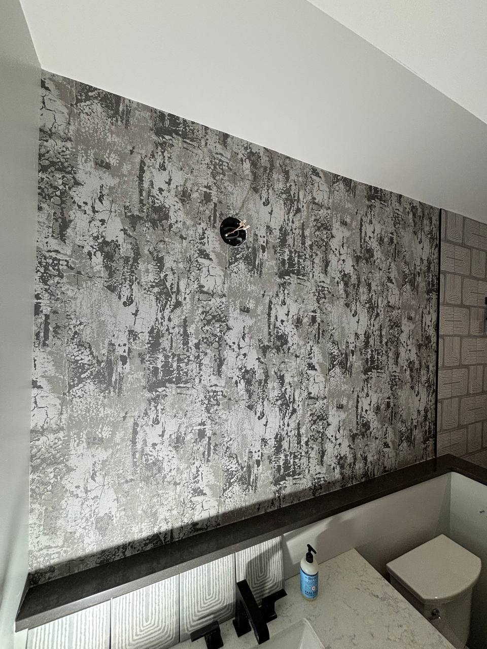 Skilled wallpaper installer applying premium wallcovering with smooth edge finishing